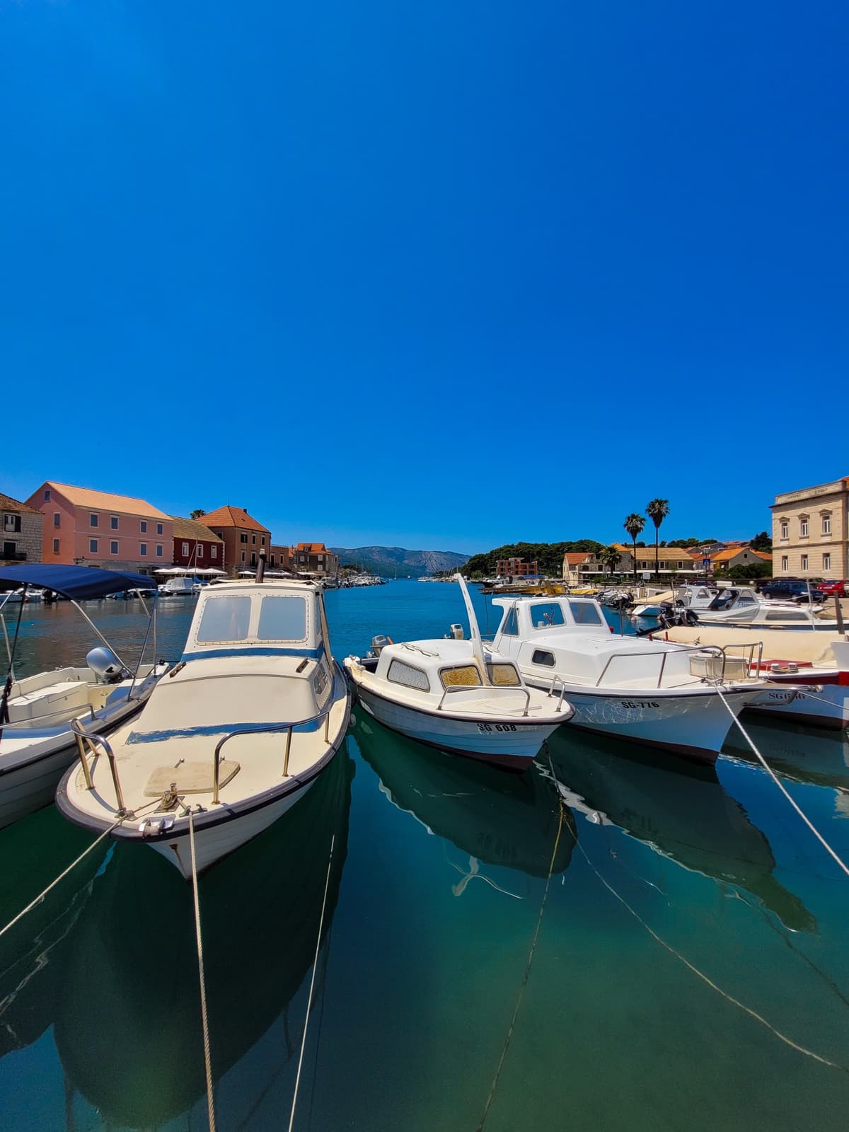 Traditional Croatian fishing boats moored in turquoise Adriatic water at Stari Grad marina, Hvar island.