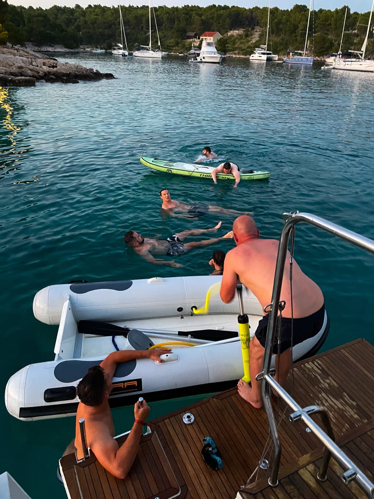 Driftawave team members swimming, snorkeling and kayaking from the anchored yacht in a turquoise Adriatic bay.