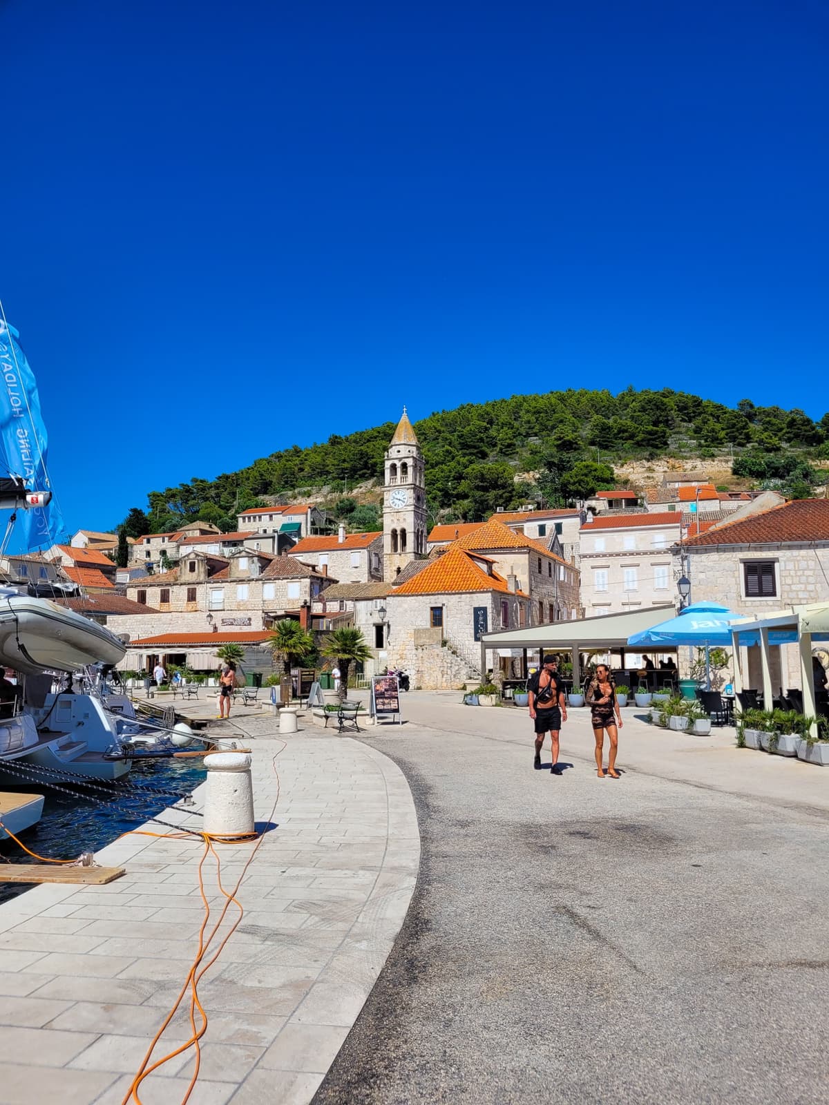 Historic Stari Grad waterfront with a stone bell tower and sailboats, a Mediterranean village in Croatia.