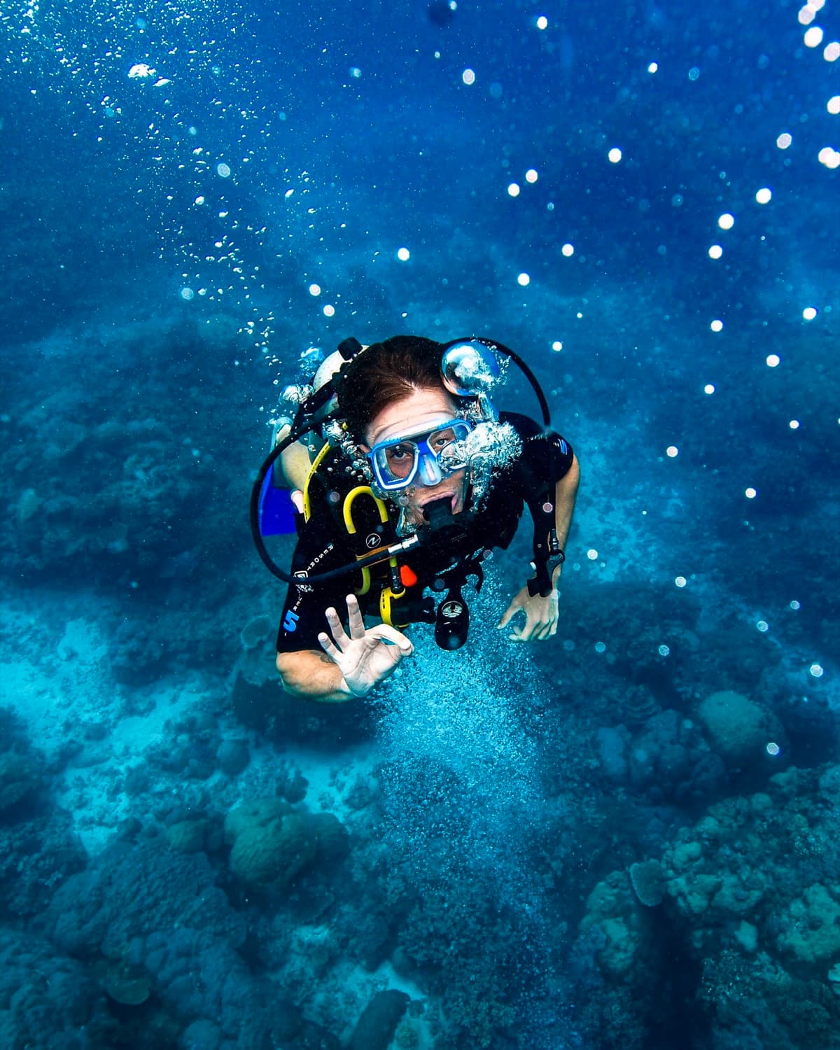 Digital nomad scuba diving in a crystal blue ocean during a workation retreat, remote work and adventure lifestyle.