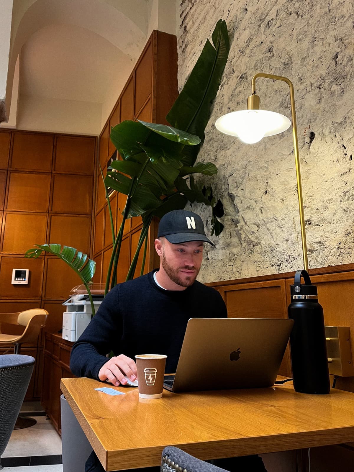 Digital nomad brand designer working remotely from a stylish cafe with a laptop and coffee, coworking lifestyle in Portugal.