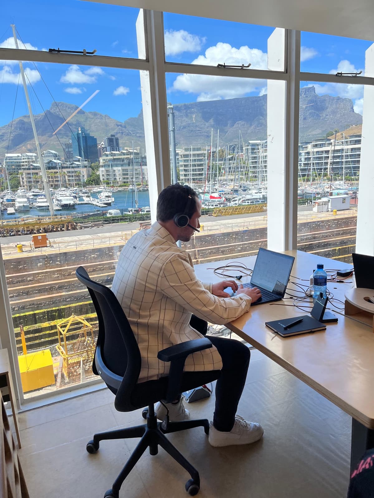 Staffinghouse team member working on a laptop overlooking Cape Town harbor and Table Mountain during a company workation.