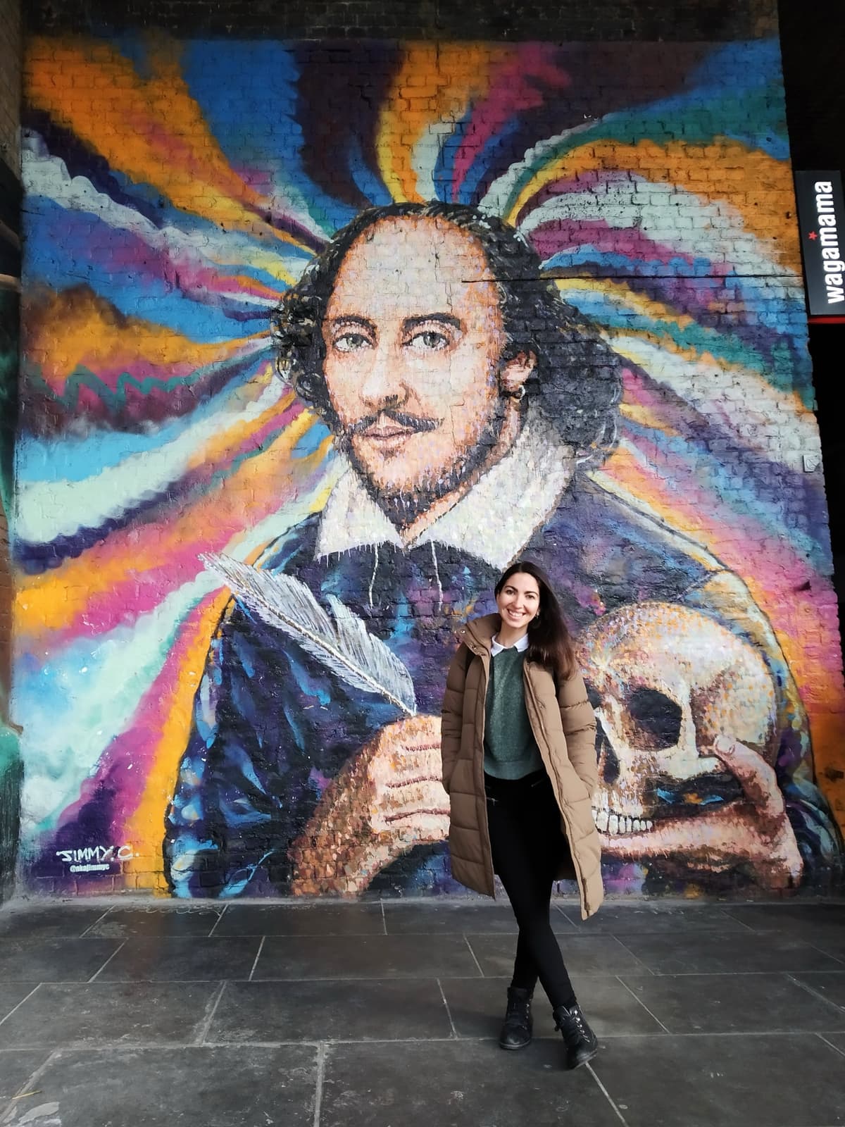 PR strategist Alexia de Souza exploring London street art at a Shakespeare mural during international travels.