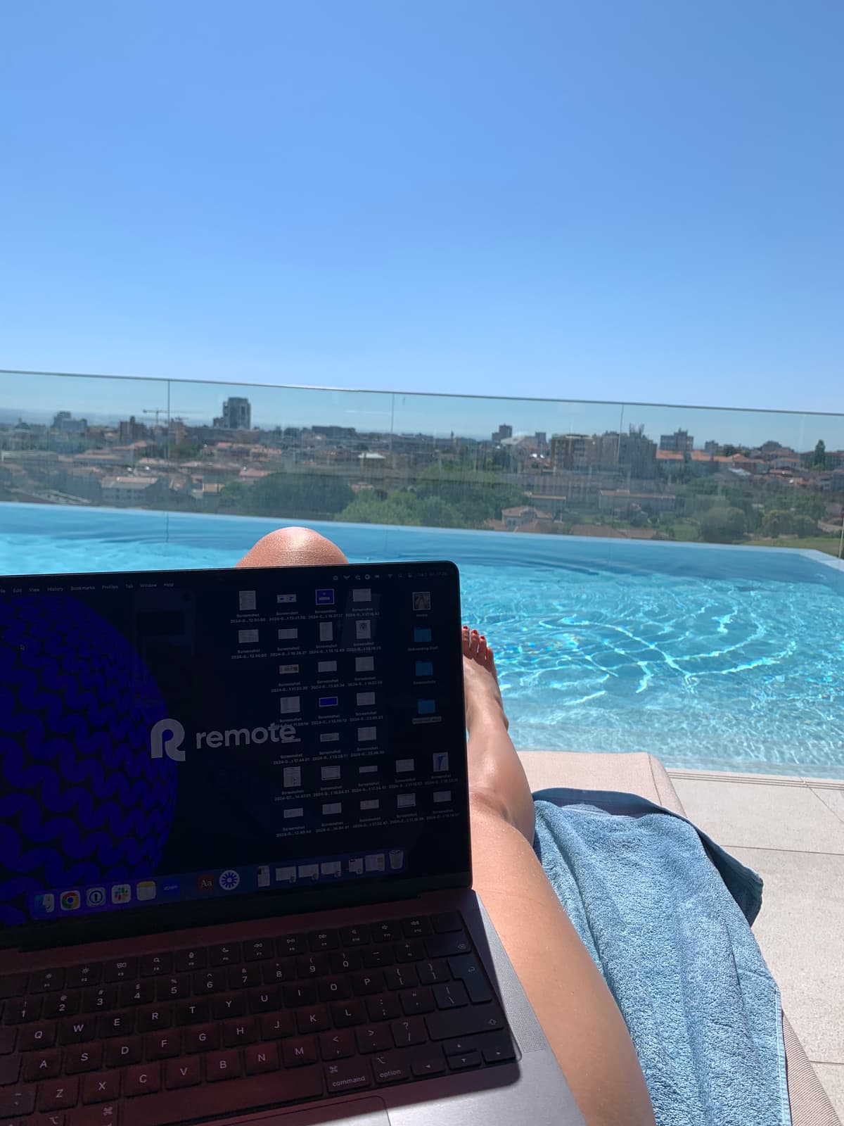 Remote.com poolside workation laptop setup with European rooftop city views.