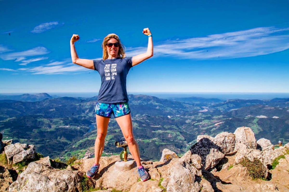 Workplace burnout researcher Sally Clarke at a mountain summit celebrating resilience, leadership strength and mental health recovery