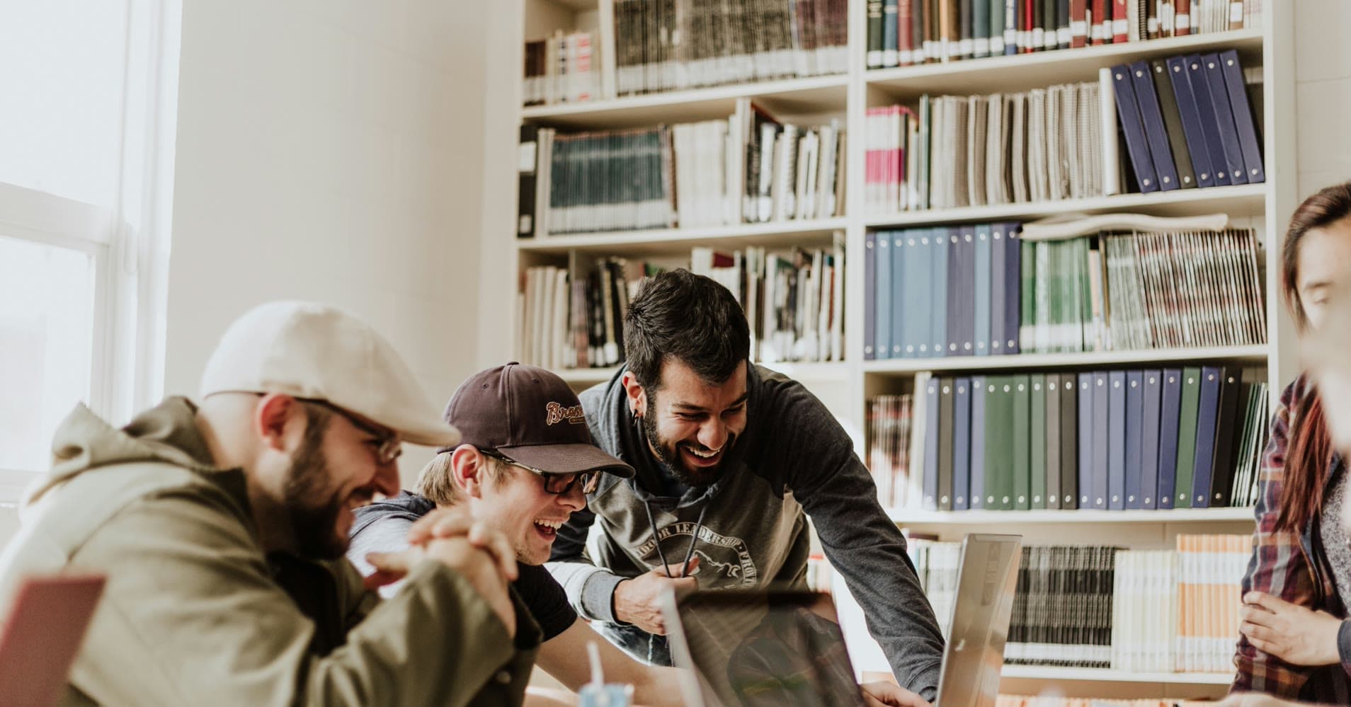 A diverse remote team laughing together around a laptop during a creative brainstorming session at a company offsite.
