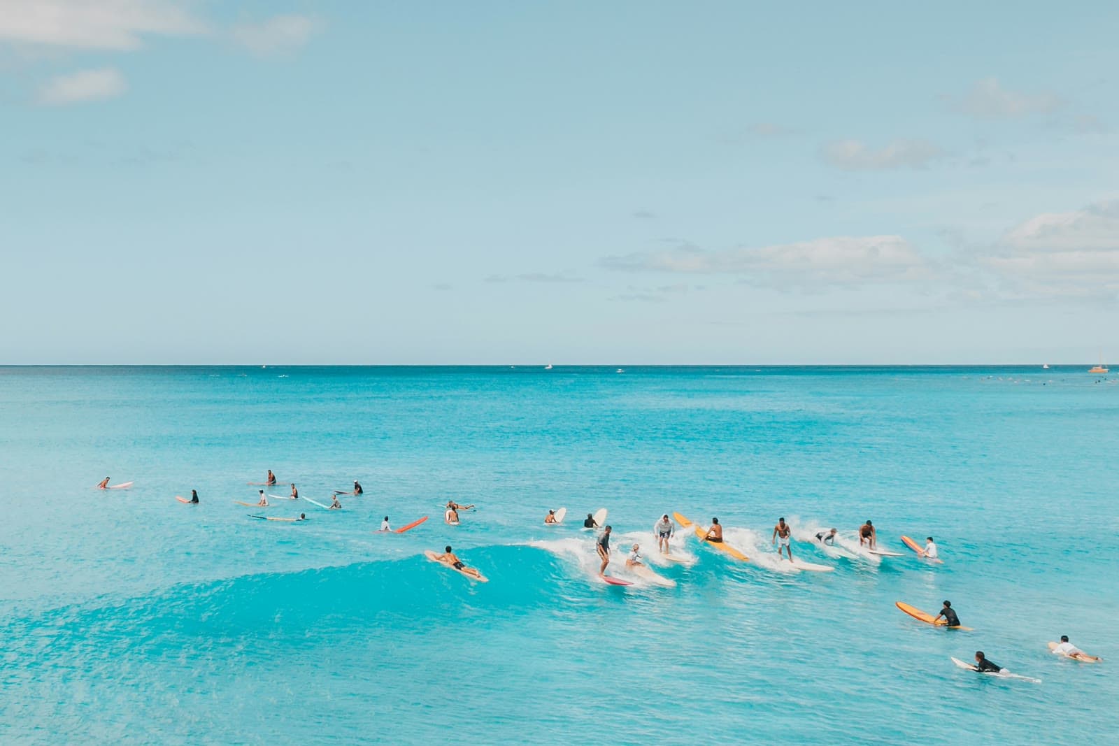 A large group of remote workers surfing together in the ocean during a company beach retreat.