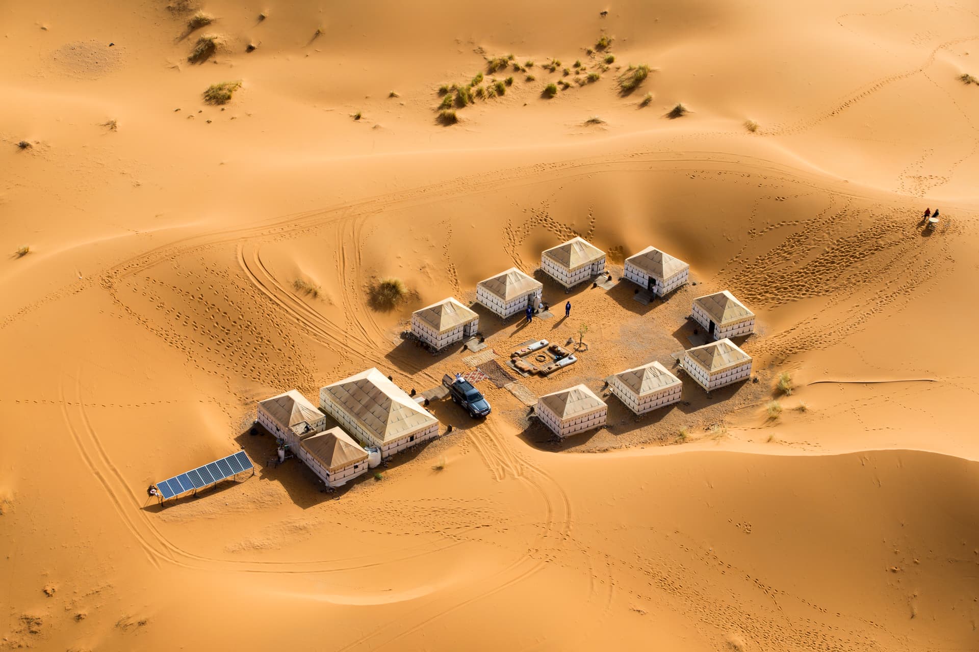 Aerial view of a desert camp with tents arranged around a fire pit in the Moroccan dunes