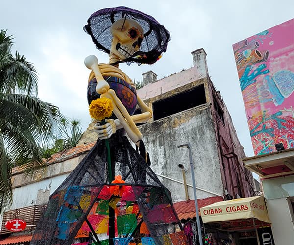 A Día de los Muertos Catrina towering over a Playa del Carmen street, culture walk on a company offsite