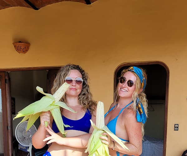 Two team members with fresh corn at the villa door in Sayulita, downtime on a surf workation