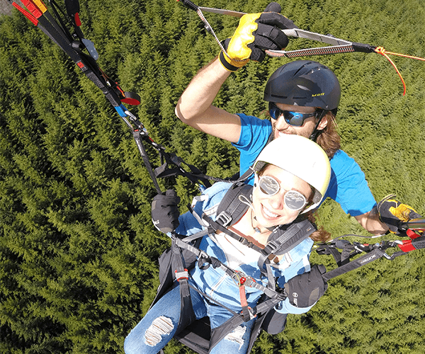 Tandem paragliding over the forest near Queenstown, finding the edge on a company offsite