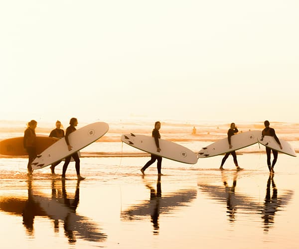 Team carrying surfboards at sunrise for surf and strategy retreat on Portugal Atlantic coast