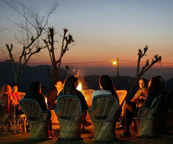 Remote team fireside bonding session with sunset mountain views during company nature retreat