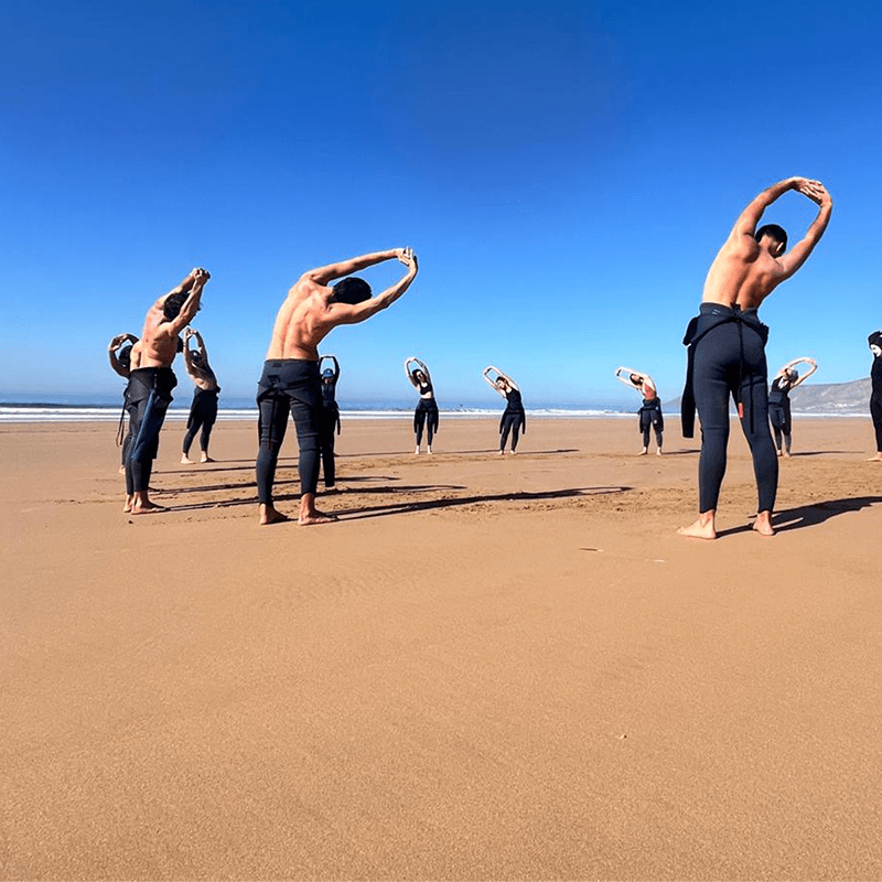 A team stretching on the beach at sunrise, the way a Driftawave team retreat starts the day