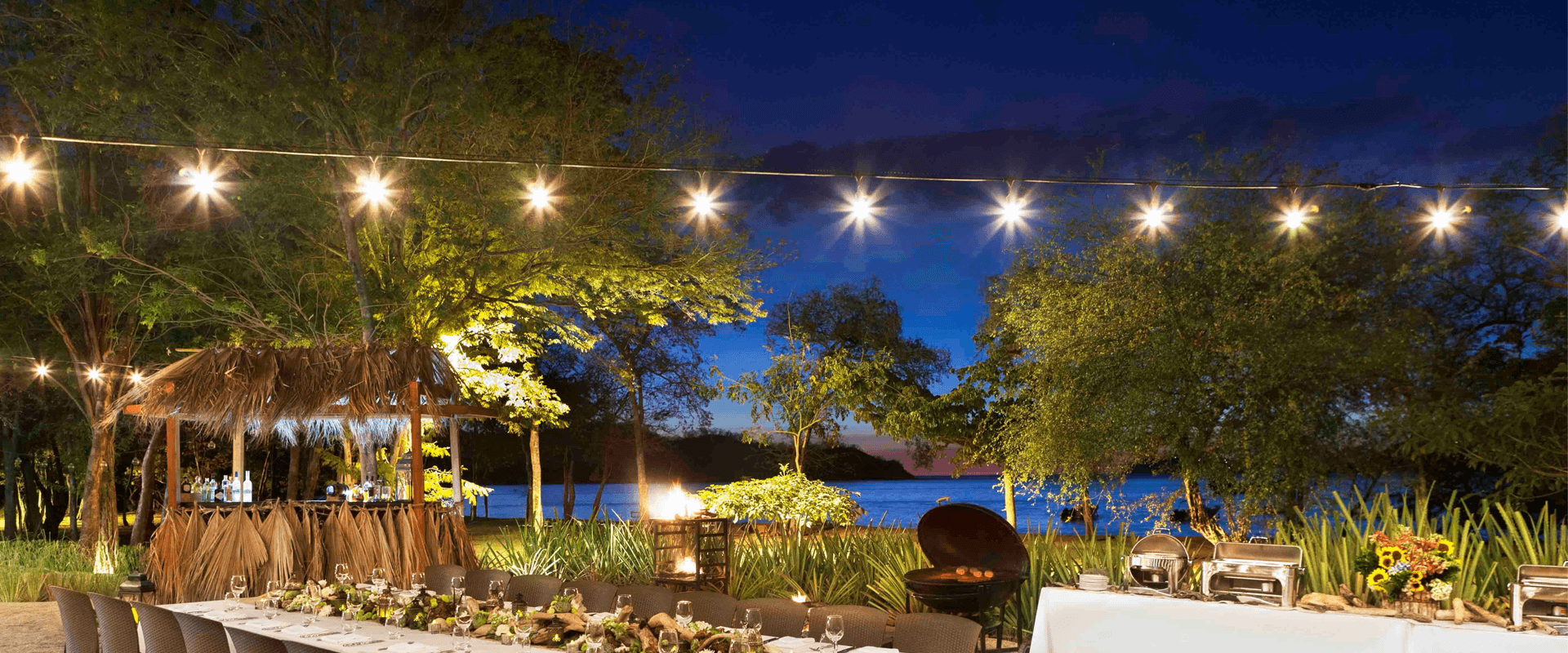 String lights over a waterfront venue at dusk, the dinner setting of a leadership team retreat