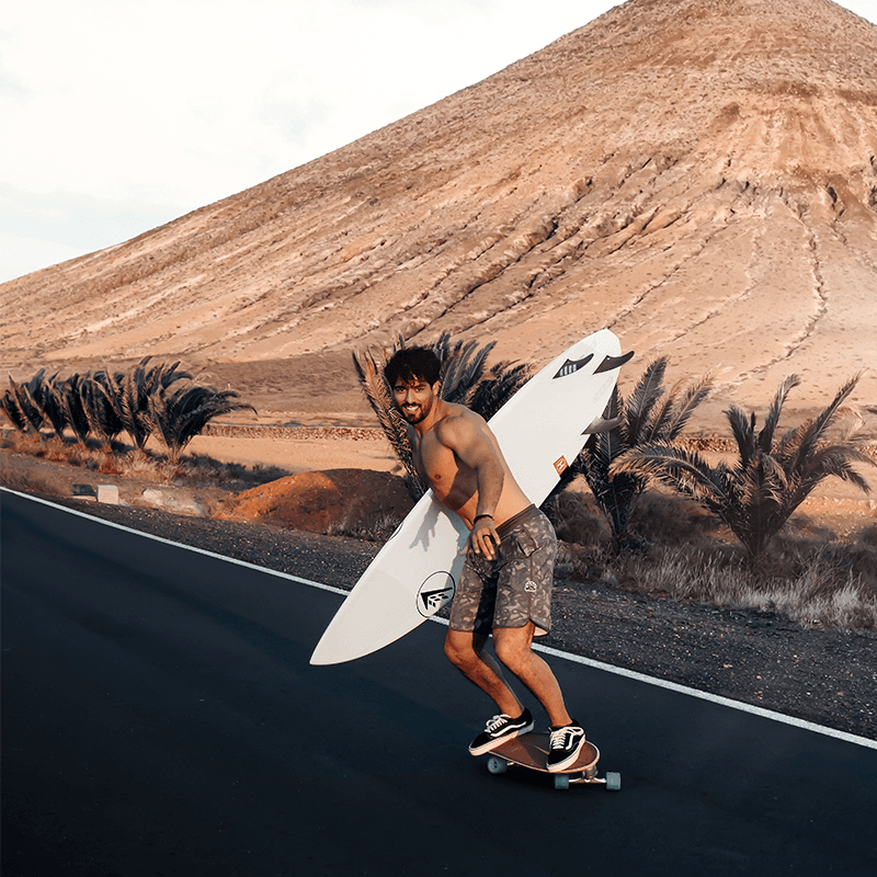 Carrying the board down a volcanic road on Gran Canaria, surf day of a marketing team retreat
