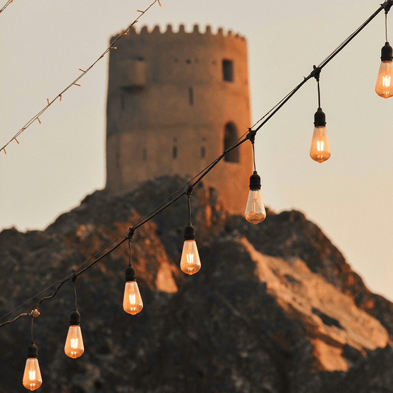 String lights strung against an ancient hilltop fortress, evening setting of a communication team retreat