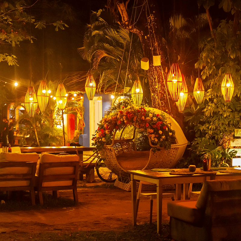 A tropical garden lounge under hanging lanterns, where a company offsite turns into a celebration