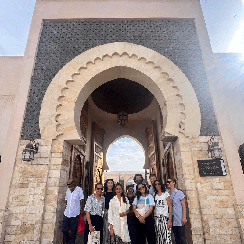 A team under a Moroccan gateway arch, culture immersion on a team retreat